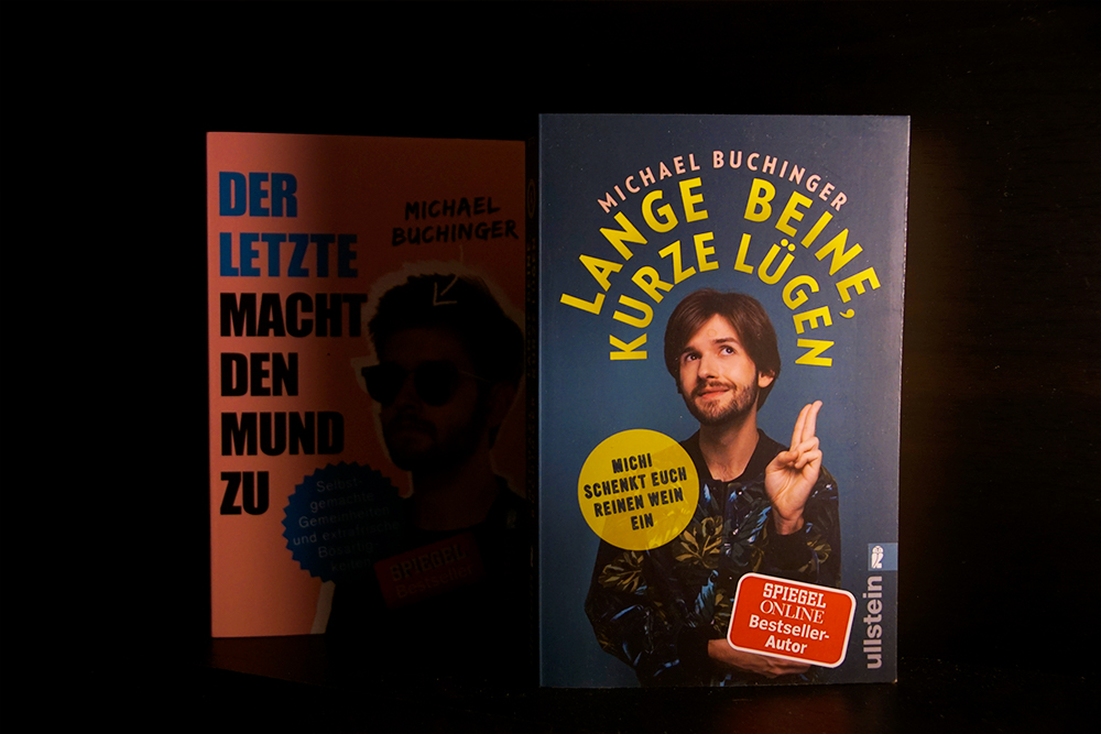 Foto vom Buchcover Lange Beine Kurze Lügen. Im Hintergrund: Michael Buchingers Debütroman. 